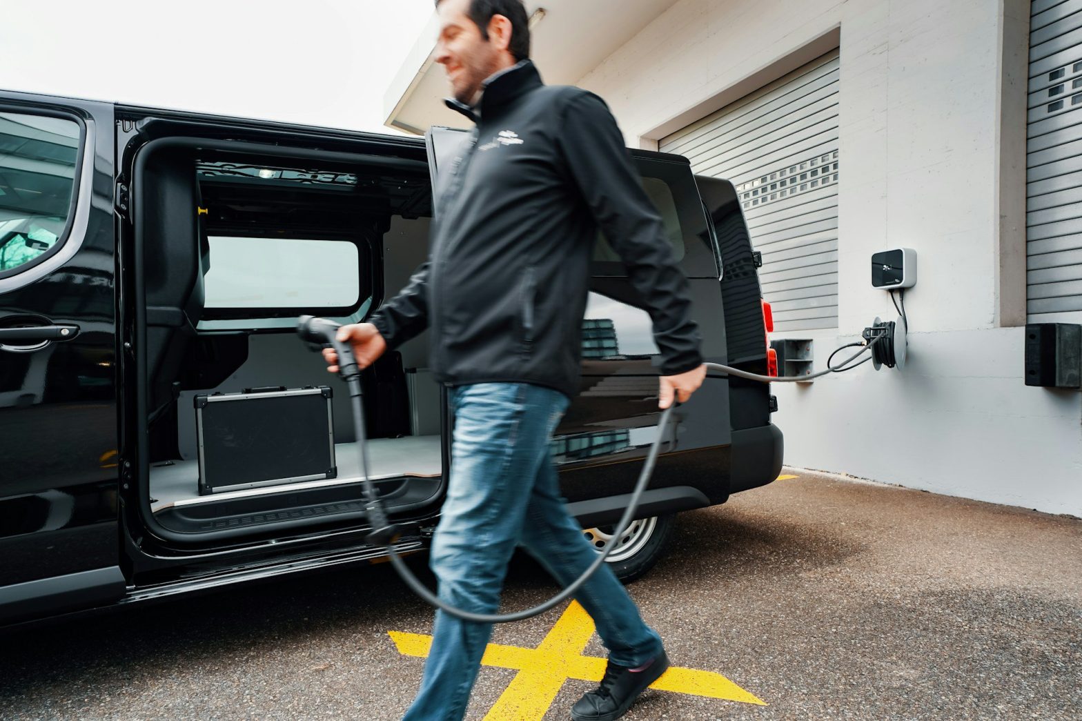 A man walking a dog in front of a black van